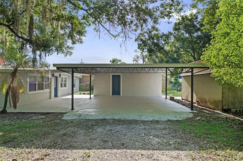 A covered concrete carport area sits in front of a house with a blue door — 929 ADRIAN COURT, LAKELAND, FL