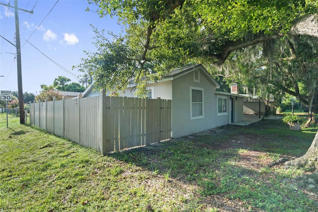 A light-colored house with a wooden fence and a large tree in the yard — 929 ADRIAN COURT, LAKELAND, FL