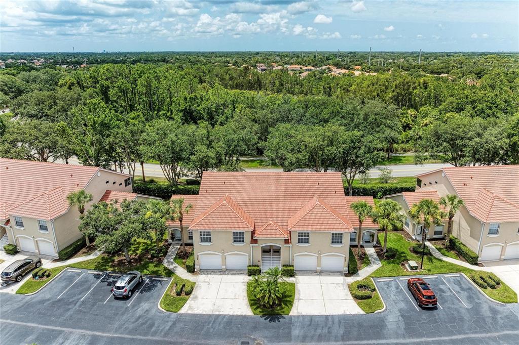 An aerial view shows a multi-unit residential building with a tiled roof and parking lot — 7126 CEDAR HOLLOW CIRCLE, BRADENTON, FL