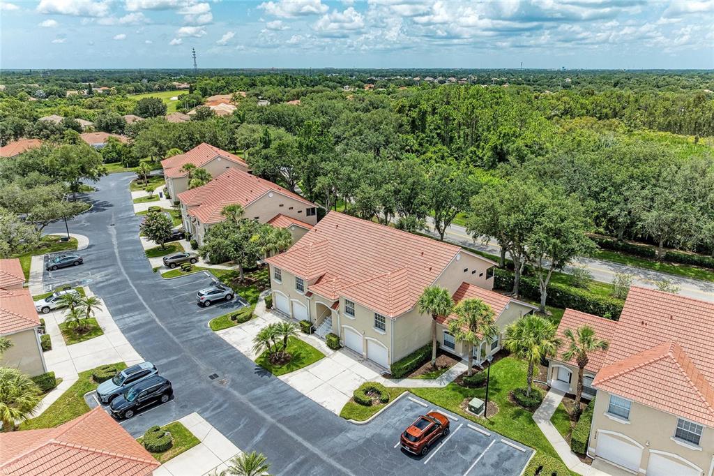 An aerial view shows several tan townhomes with red tile roofs and parking areas — 7126 CEDAR HOLLOW CIRCLE, BRADENTON, FL