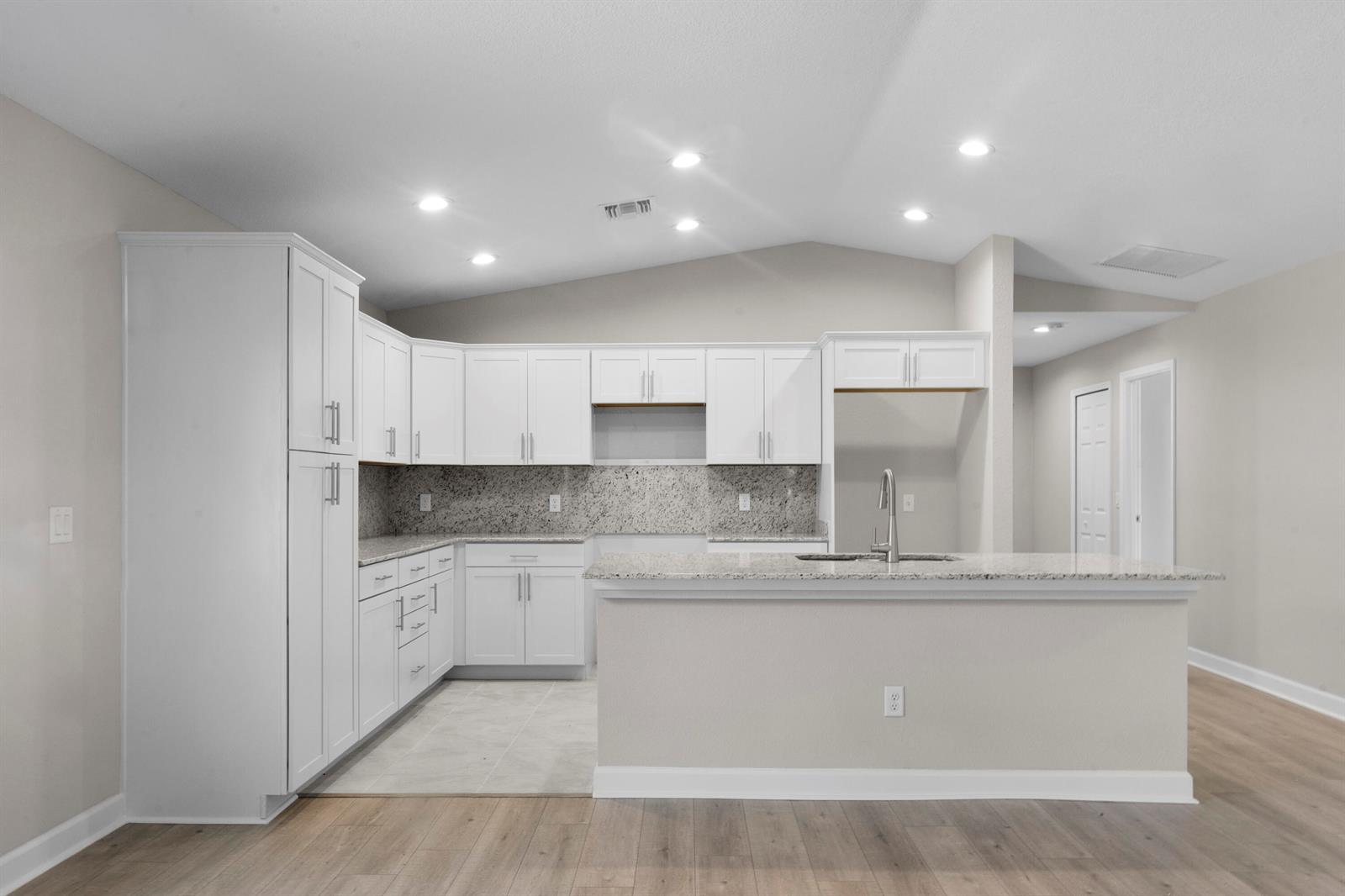 A kitchen features white cabinets, granite countertops, a center island, and light-colored flooring — 41 La Villa Way, Fort Pierce FL 34951, FORT PIERCE, FL