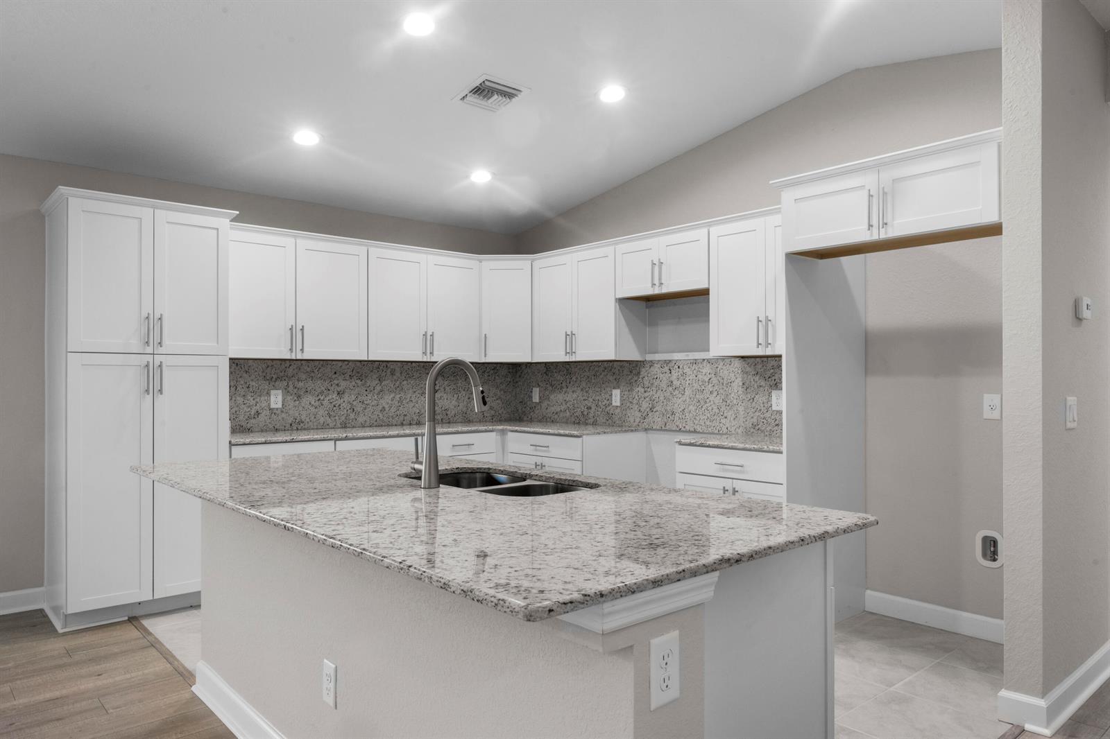 A kitchen features white cabinetry, granite countertops, a central island, and recessed ceiling lighting — 41 La Villa Way, Fort Pierce FL 34951, FORT PIERCE, FL