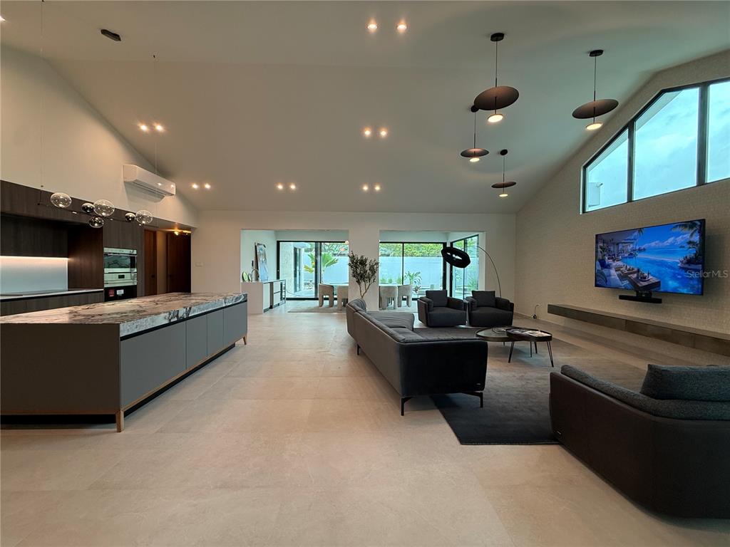 A modern open-concept living area features a large kitchen island, gray sofas, and vaulted ceilings — 241 CAMINO DEL JAGUEY, DORADO, PR