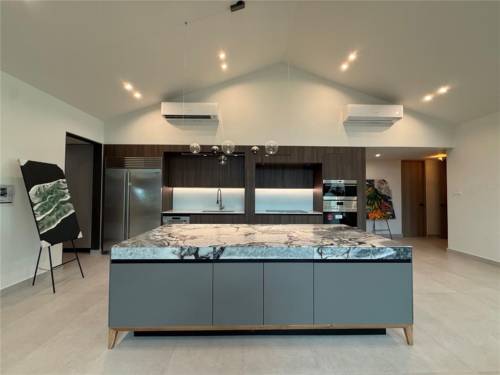 A modern kitchen features a large marble-topped island, dark wood cabinetry, and two wall-mounted air conditioners — 241 CAMINO DEL JAGUEY, DORADO, PR