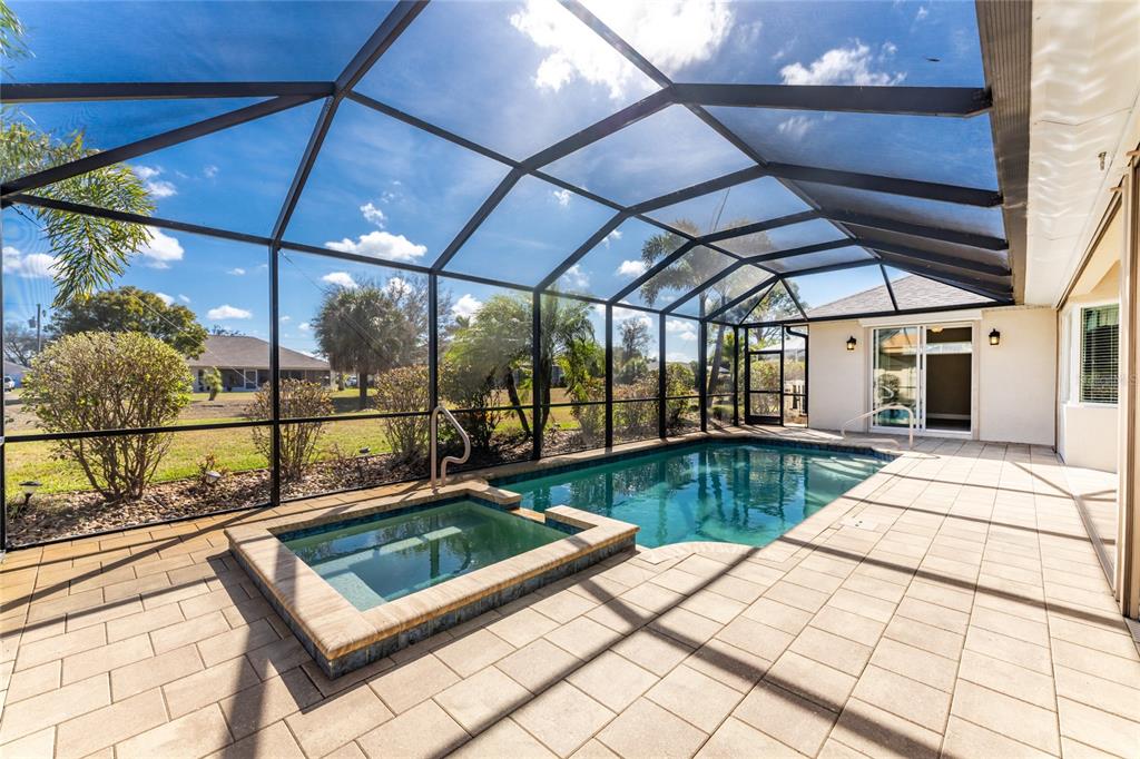 A screened-in patio features a swimming pool, a raised spa, and light-colored paver flooring — 250 ROTONDA BOULEVARD N, ROTONDA WEST, FL
