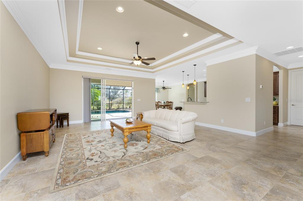 A living room with a tray ceiling, tile floors, and a view of a pool — 250 ROTONDA BOULEVARD N, ROTONDA WEST, FL