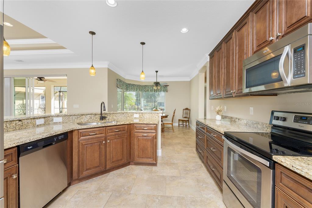 A kitchen with wood cabinets, granite countertops, stainless steel appliances, and tile flooring — 250 ROTONDA BOULEVARD N, ROTONDA WEST, FL