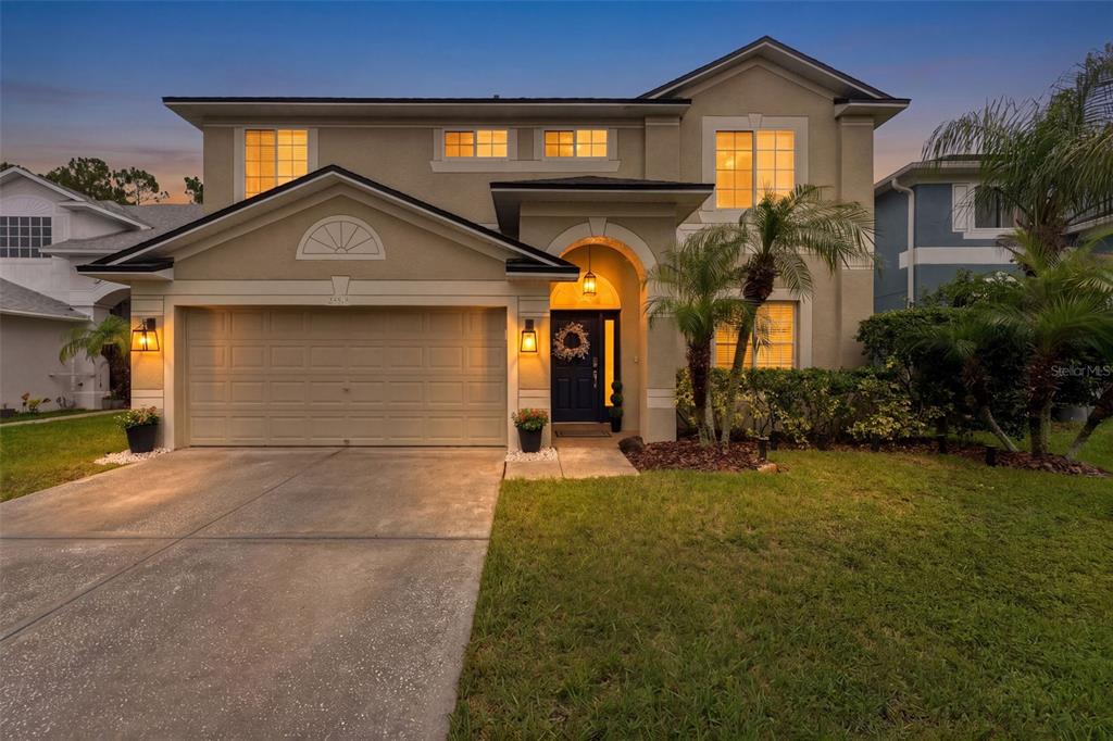 A two-story suburban house with a beige stucco exterior, a garage, and a front entrance — 25515 BRUFORD BLVD, LAND O LAKES, FL