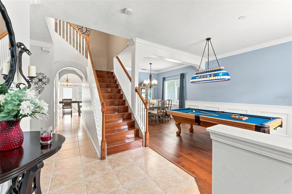 A foyer with tile flooring leads to a staircase, a dining area, and a pool table — 25515 BRUFORD BLVD, LAND O LAKES, FL