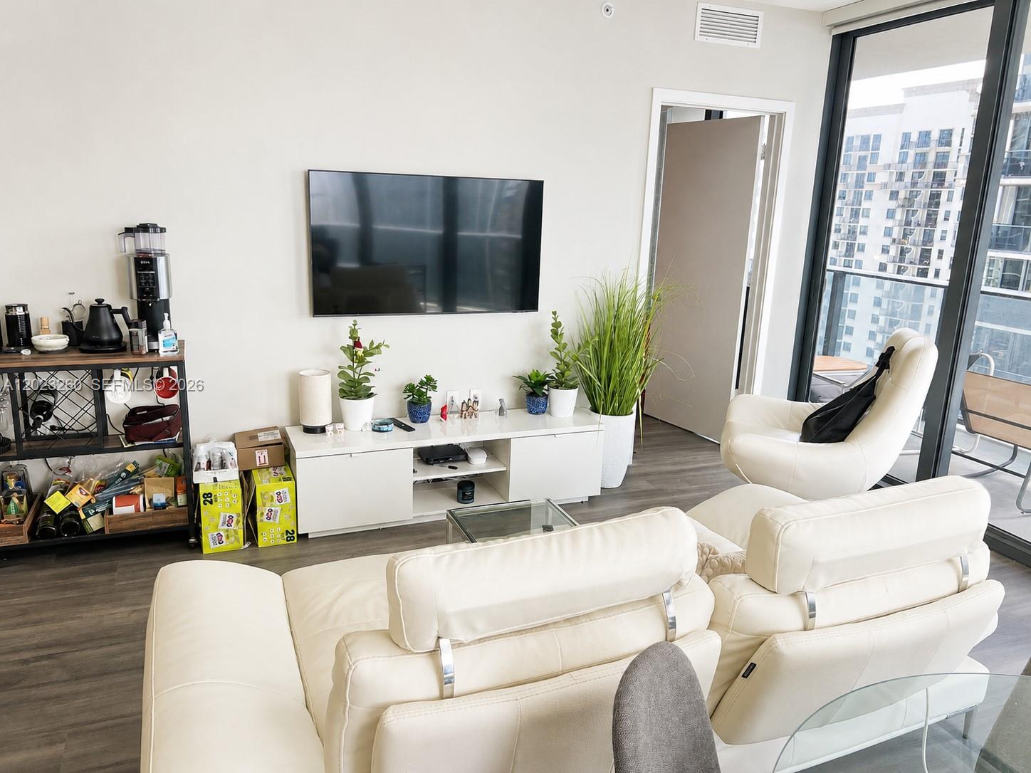 A living room features a white media console, a wall-mounted television, and white leather seating — 45 SW 9th St # 2908, Miami FL 33130, MIAMI, FL