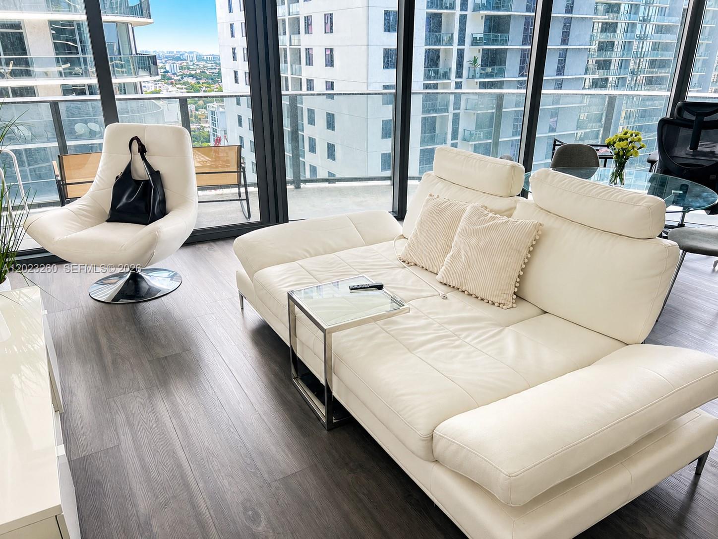 A modern living room features a white leather sofa, a swivel chair, and floor-to-ceiling windows — 45 SW 9th St # 2908, Miami FL 33130, MIAMI, FL