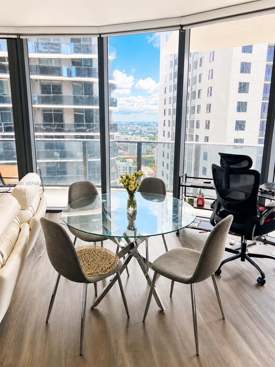 A dining area with a glass table and four chairs sits before floor-to-ceiling windows — 45 SW 9th St # 2908, Miami FL 33130, MIAMI, FL
