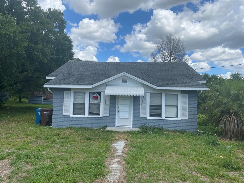 A single-story house with gray brick siding, white shutters, and a white front door — 431 S MIAMI STREET, LAKE WALES, FL
