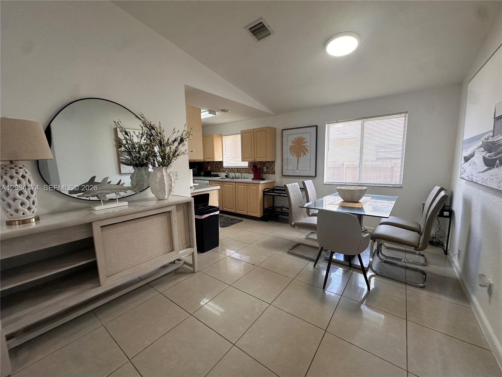 A dining area with tile floors, a glass table, and an adjacent kitchen with cabinets — 404 NW 2nd Ave # A, Hallandale Beach FL 33009, HALLANDALE BEACH, FL