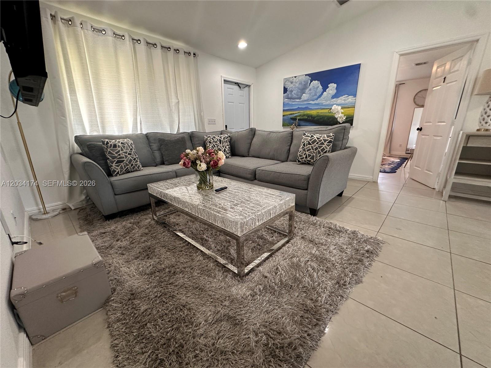 A living room features a gray sectional sofa, a textured coffee table, and a shag rug — 404 NW 2nd Ave # A, Hallandale Beach FL 33009, HALLANDALE BEACH, FL