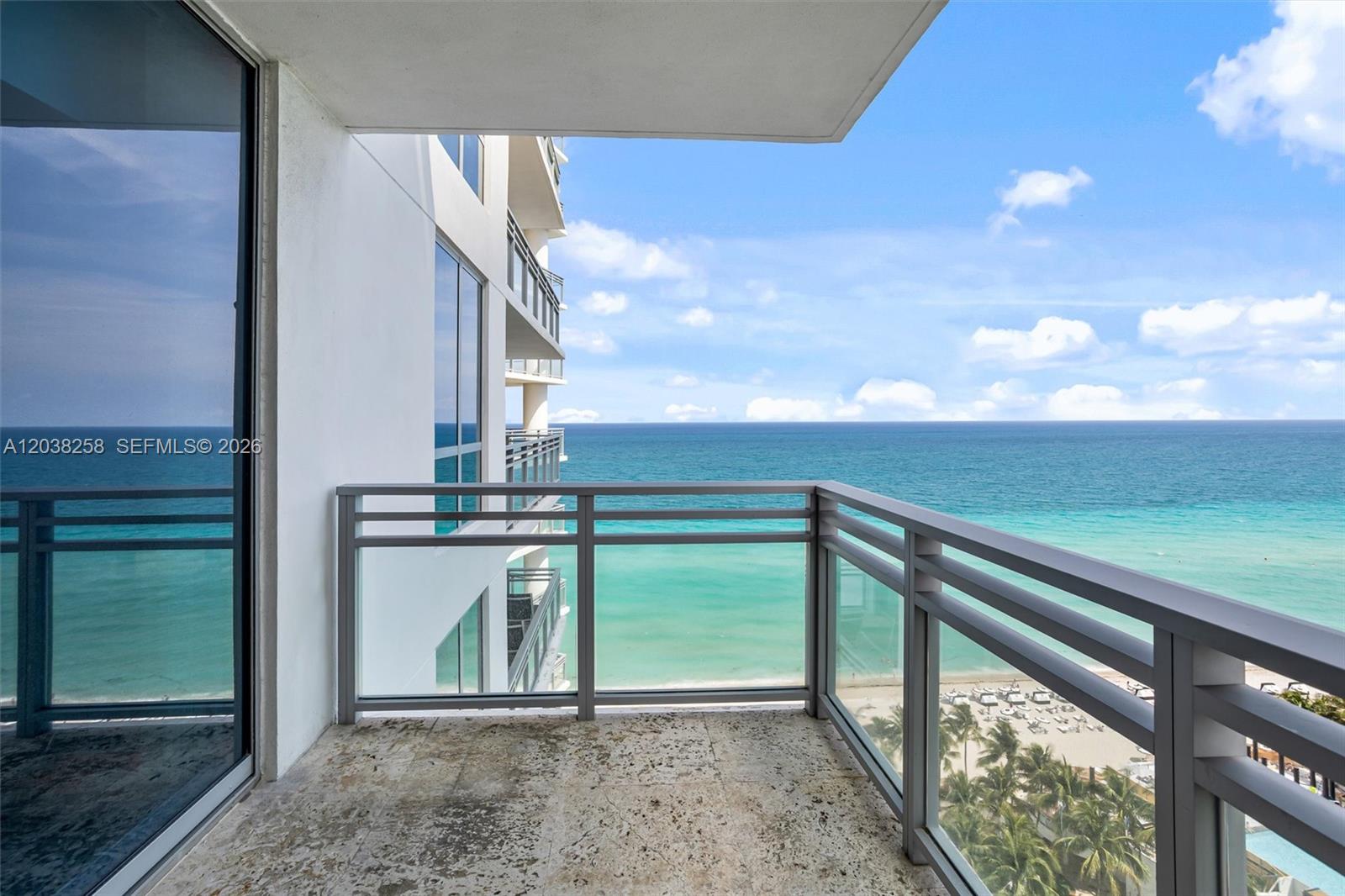 A balcony with a glass railing overlooks the ocean and a sandy beach below — 3535 S Ocean Dr # 1703, Hollywood FL 33019, HOLLYWOOD, FL