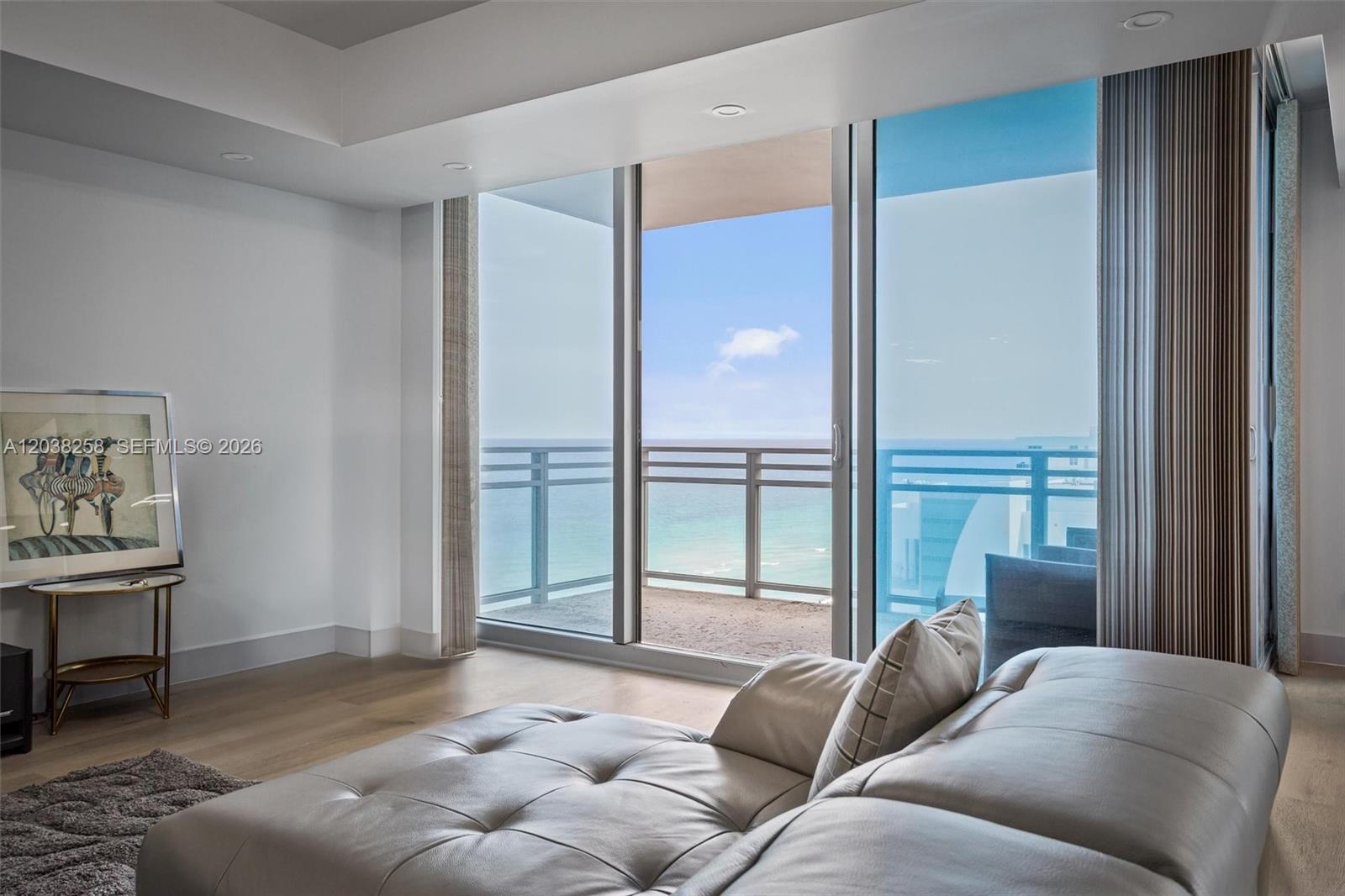 A living room features a tufted leather sofa, light wood floors, and a balcony view — 3535 S Ocean Dr # 1703, Hollywood FL 33019, HOLLYWOOD, FL