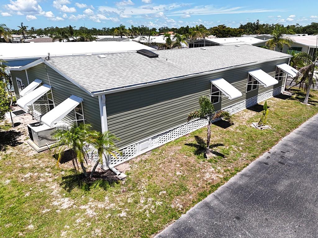 An aerial view of a green manufactured home with a shingled roof and window awnings — 15550 BURNT STORE ROAD UNIT 154, PUNTA GORDA, FL