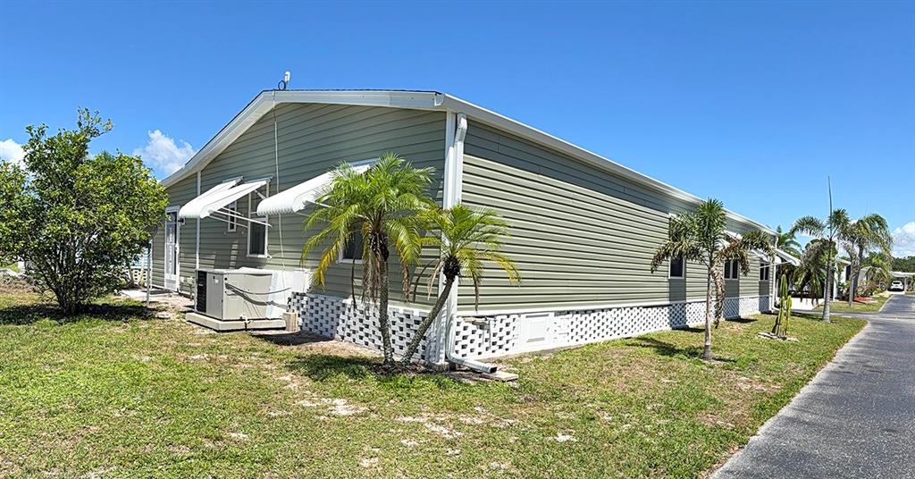 The exterior of a light green manufactured home features white lattice skirting and palm trees — 15550 BURNT STORE ROAD UNIT 154, PUNTA GORDA, FL