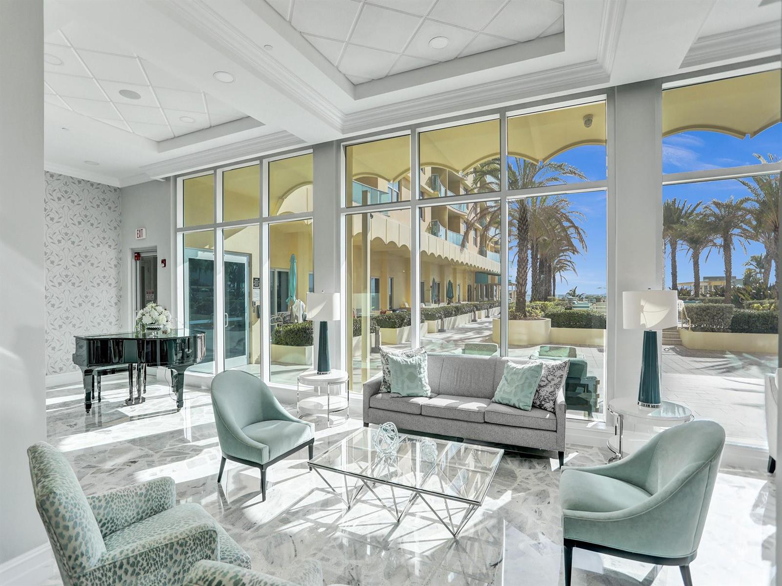 A bright lobby features a grand piano, seating area, and floor-to-ceiling windows overlooking a patio — 2501 S Ocean Drive # 338, Hollywood FL 33019, HOLLYWOOD, FL