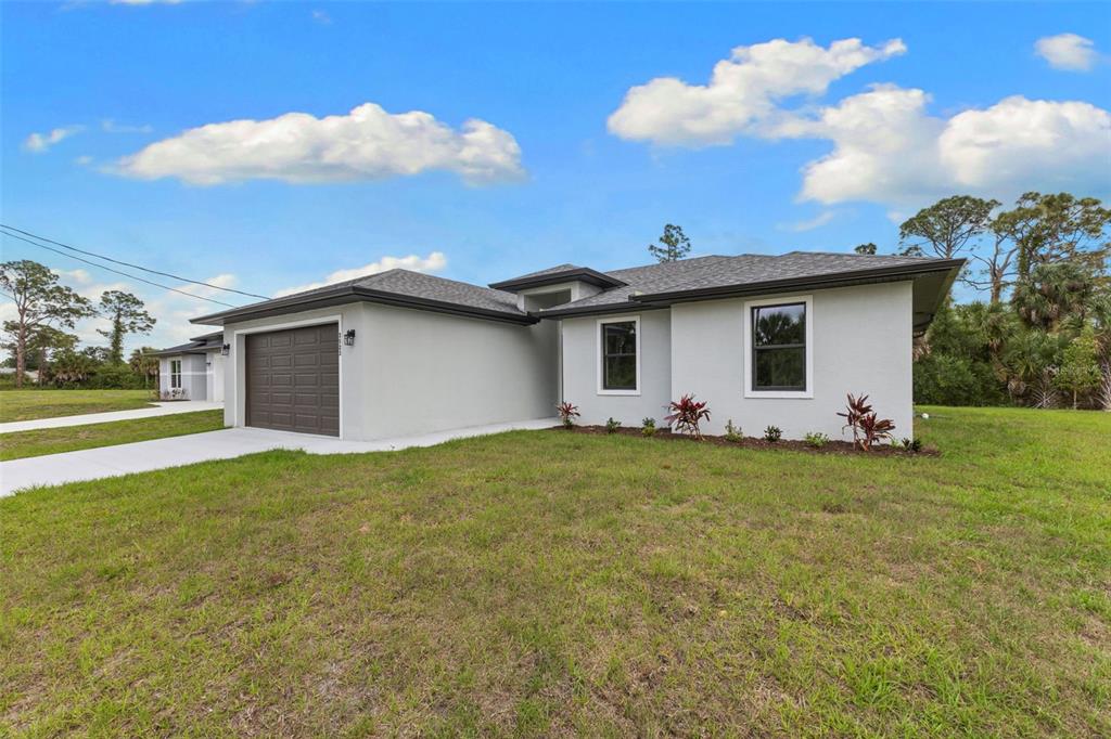 A single-story house with a gray stucco exterior, a brown garage door, and a lawn — 2523 WYOLA AVENUE, NORTH PORT, FL