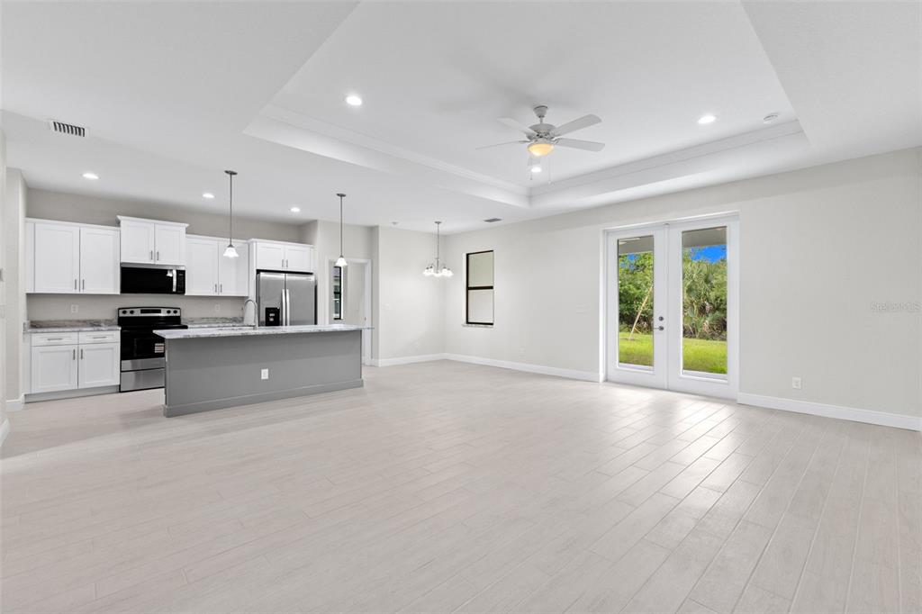 A bright, open-concept kitchen and living area features white cabinets, a gray island, and tile flooring — 2523 WYOLA AVENUE, NORTH PORT, FL