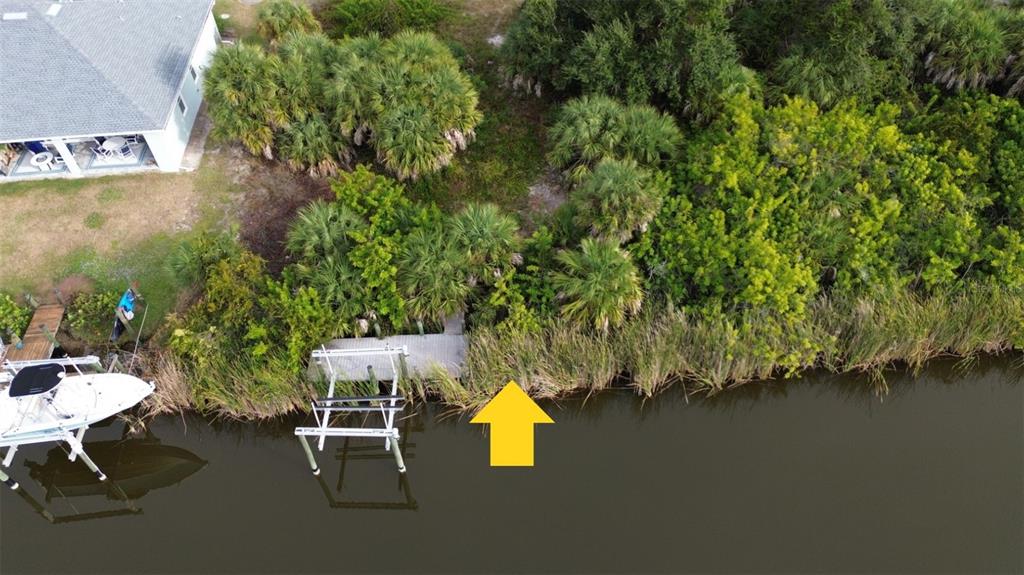 An aerial view shows a boat dock and lift along a canal next to vegetation — 13281 LONGVILLE AVENUE, PORT CHARLOTTE, FL