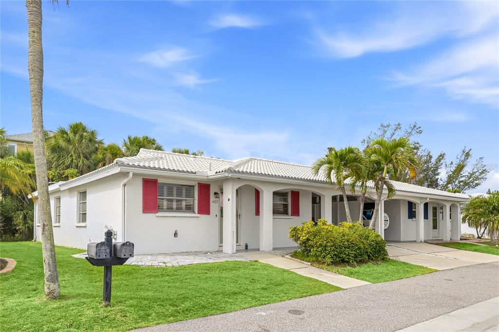 A single-story white house with red shutters and a palm tree in the front yard — 602 SPANISH DRIVE S UNIT 115, LONGBOAT KEY, FL