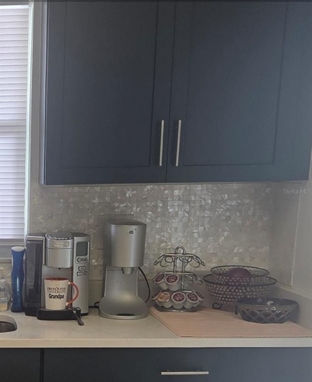 A kitchen counter features dark cabinets, a mother-of-pearl backsplash, and two coffee makers — 3288 LAKE BAYSHORE DRIVE UNIT 523, BRADENTON, FL