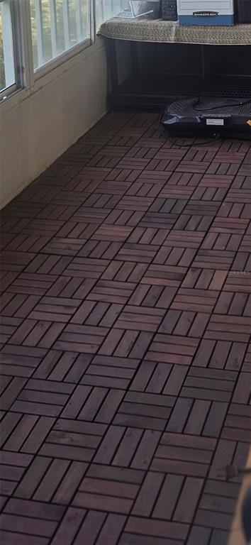 A sunroom features dark wood-look interlocking deck tiles covering the floor — 3288 LAKE BAYSHORE DRIVE UNIT 523, BRADENTON, FL