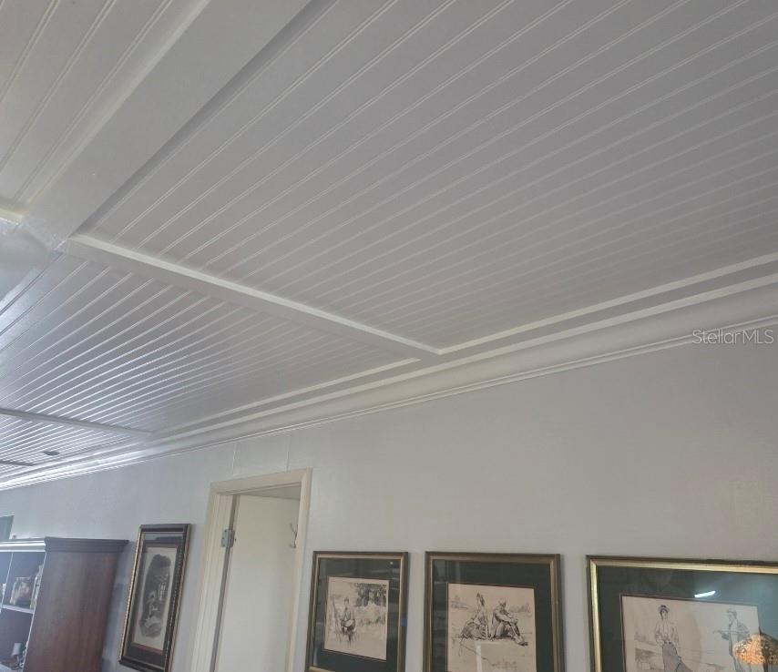A room features a white beadboard ceiling with crown molding and framed wall art — 3288 LAKE BAYSHORE DRIVE UNIT 523, BRADENTON, FL
