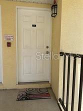 A white front door with a welcome mat is situated on a covered exterior porch — 3001 58TH AVENUE S UNIT 408, ST PETERSBURG, FL