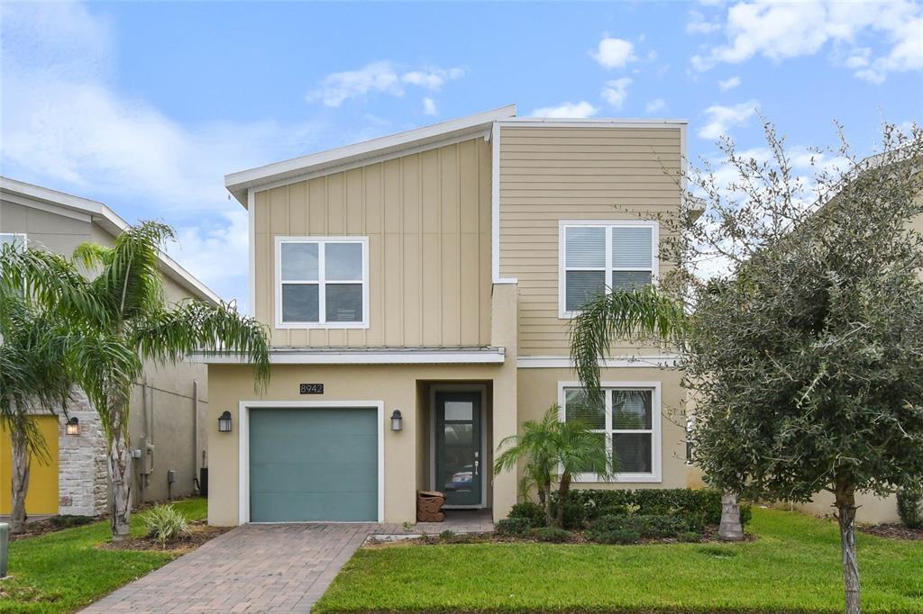 A two-story house with a tan exterior, a single-car garage, and a paved driveway — 8942 CABOT CLIFFS DRIVE, DAVENPORT, FL