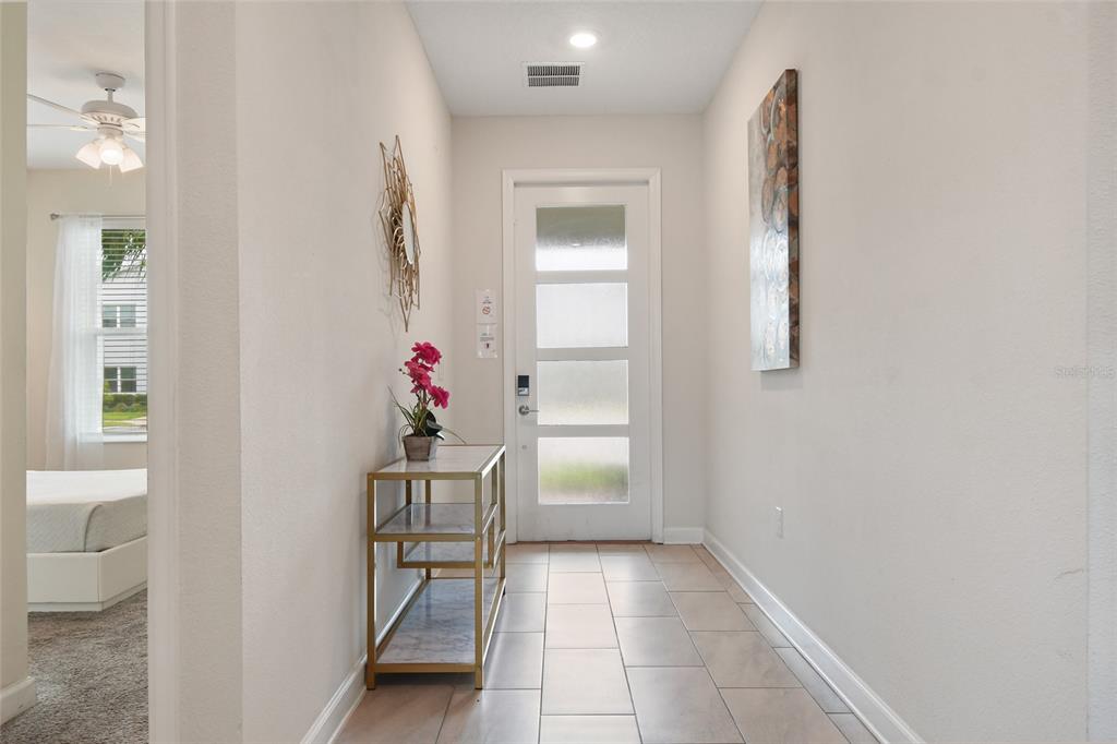A bright entryway features a white door with frosted glass panels and tiled flooring — 8942 CABOT CLIFFS DRIVE, DAVENPORT, FL