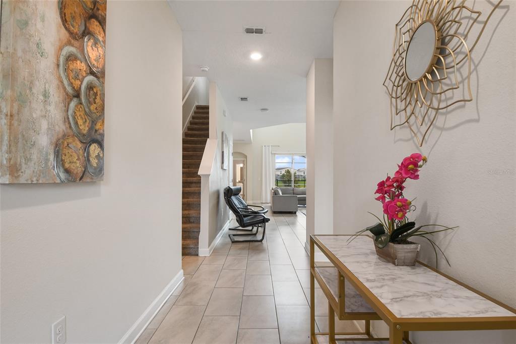 A tiled entryway leads to a staircase and a living area with a marble console — 8942 CABOT CLIFFS DRIVE, DAVENPORT, FL
