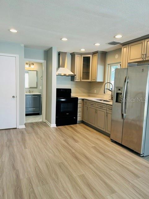 A kitchen with light wood flooring, gray cabinets, stainless steel appliances, and an adjacent bathroom — 1914 CHAMBERLIN STREET, ORLANDO, FL