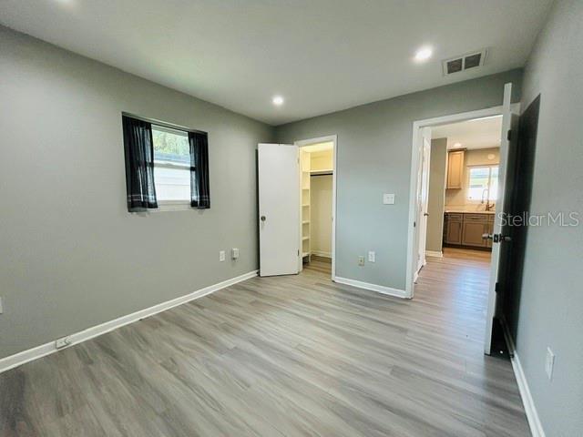 A bedroom with gray walls, wood-look flooring, a closet, and an open doorway to a kitchen — 1914 CHAMBERLIN STREET, ORLANDO, FL