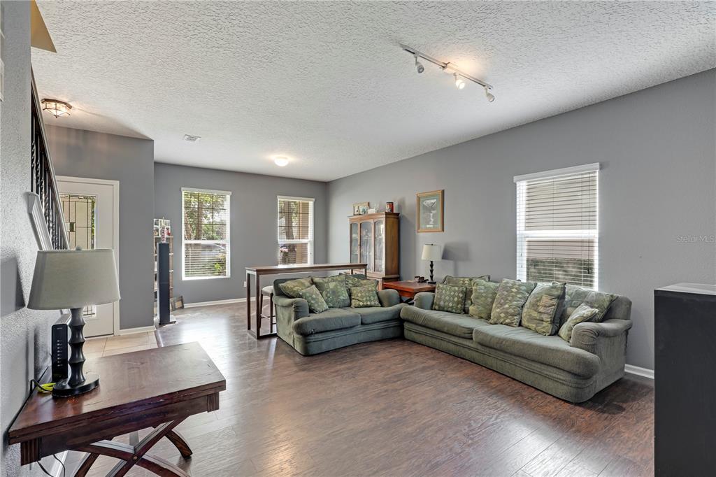 A living room features gray walls, dark wood flooring, and two green fabric sofas — 3520 OGLEBAY DRIVE, GREEN COVE SPRINGS, FL