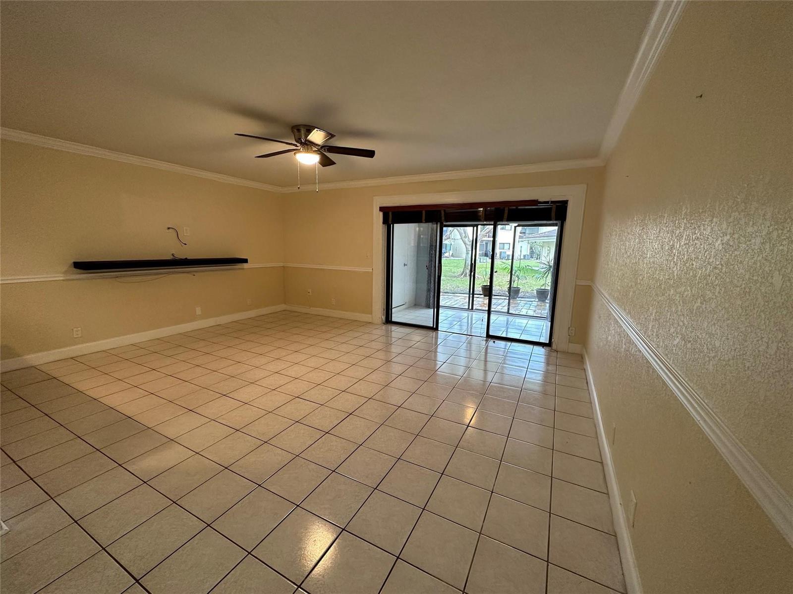 An empty living room features beige walls, tile flooring, a ceiling fan, and sliding glass doors — 22435 SW 61st Way # 124, Boca Raton FL 33428, BOCA RATON, FL