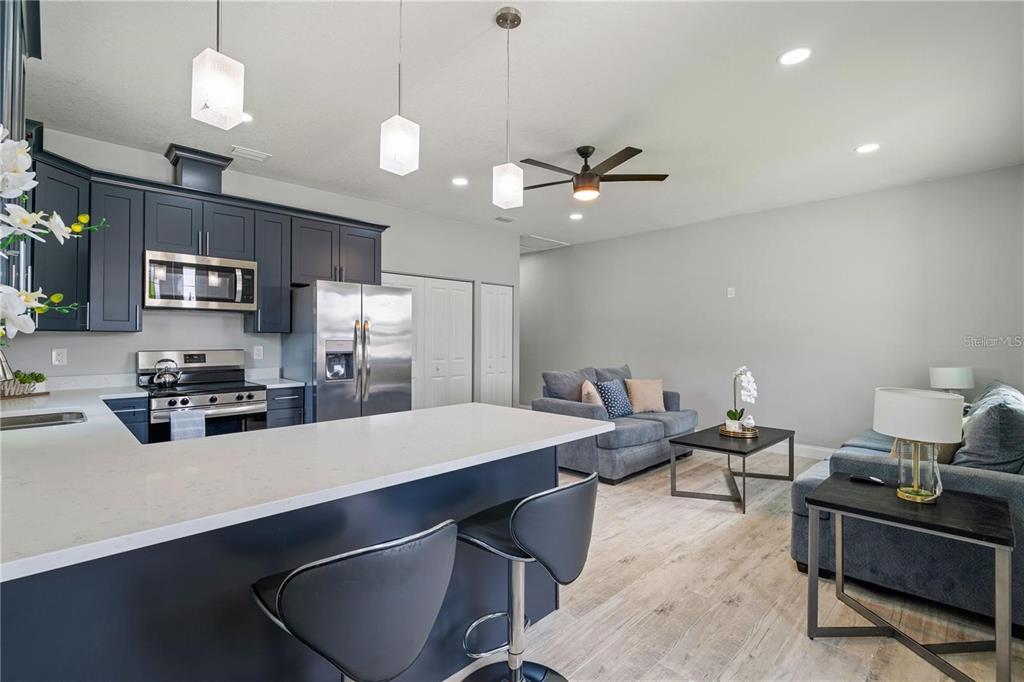 A modern kitchen with dark blue cabinets and a white island opens to a living area — 2617 W SAINT JOSEPH STREET UNIT 2, TAMPA, FL