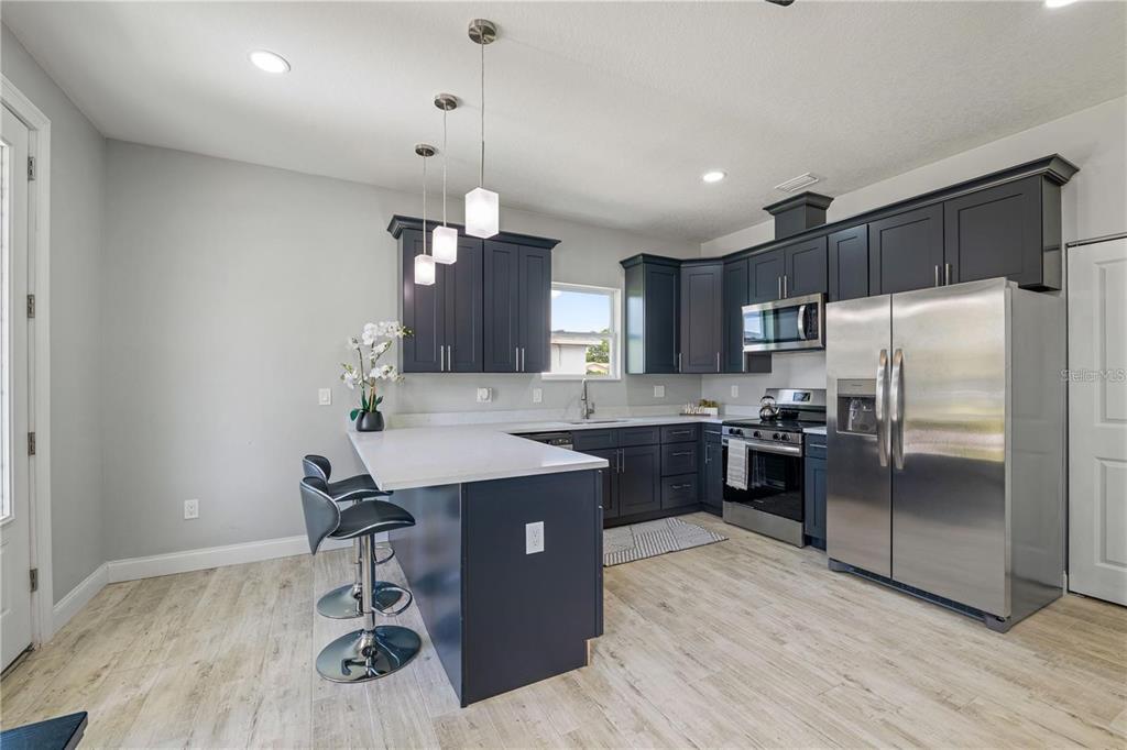 A kitchen features dark blue cabinets, stainless steel appliances, and a white quartz island countertop — 2617 W SAINT JOSEPH STREET UNIT 2, TAMPA, FL