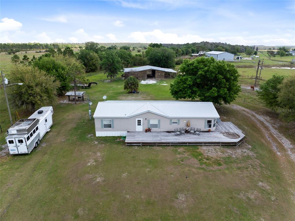 An aerial view shows a single-story house with a metal roof and a large wooden deck — 3591 N CANOE CREEK ROAD, KENANSVILLE, FL