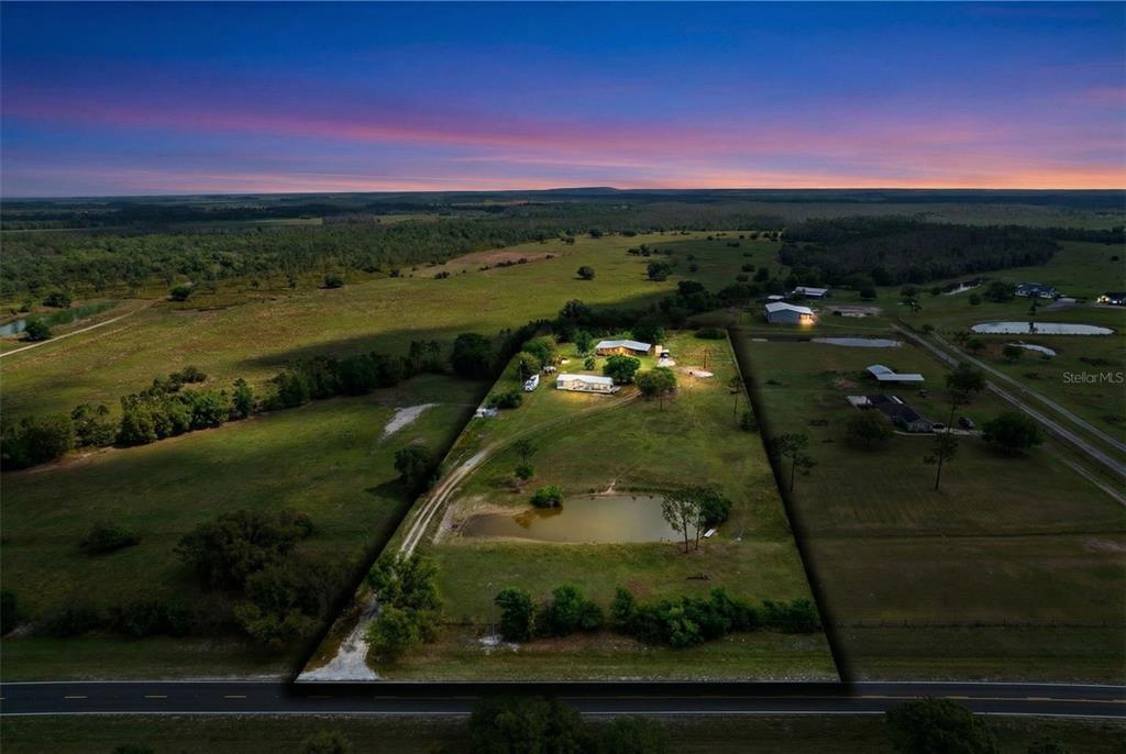 An aerial view shows a house and a pond on a large, rural grassy lot — 3591 N CANOE CREEK ROAD, KENANSVILLE, FL