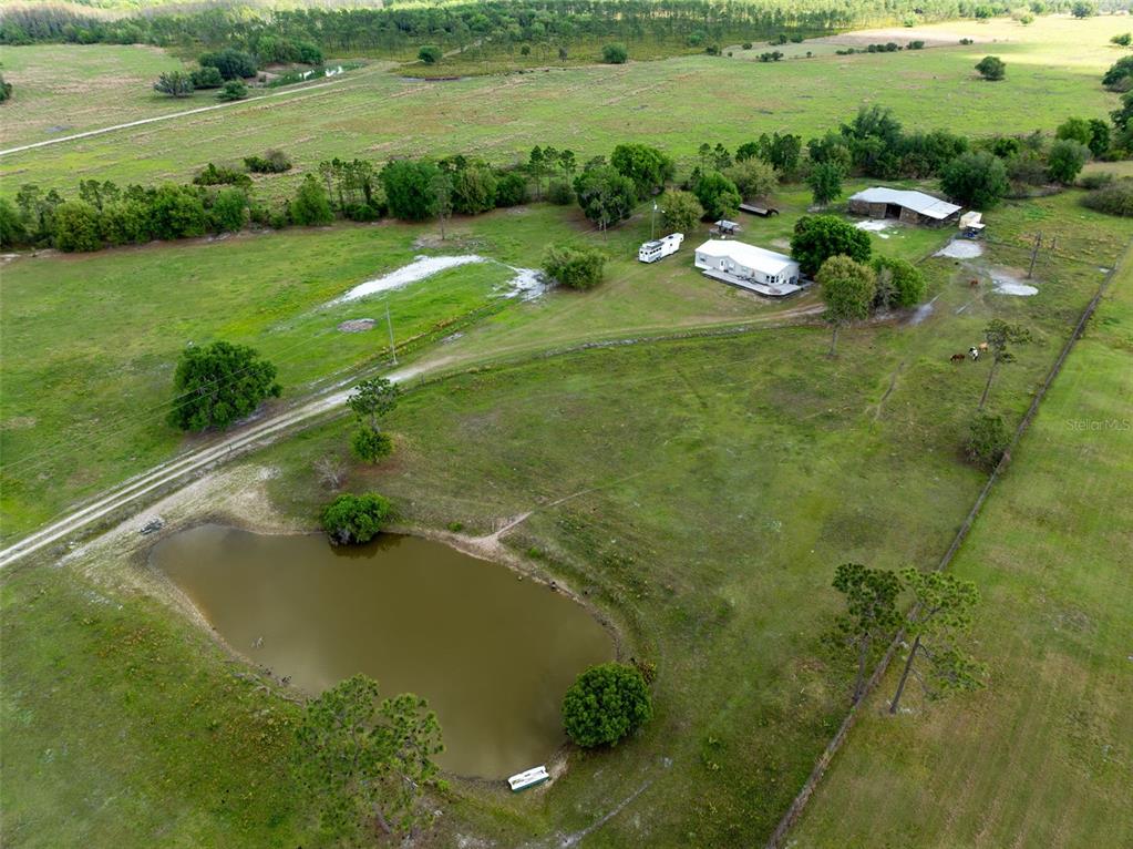An aerial view shows a rural property with a house, outbuilding, pond, and fenced pasture — 3591 N CANOE CREEK ROAD, KENANSVILLE, FL