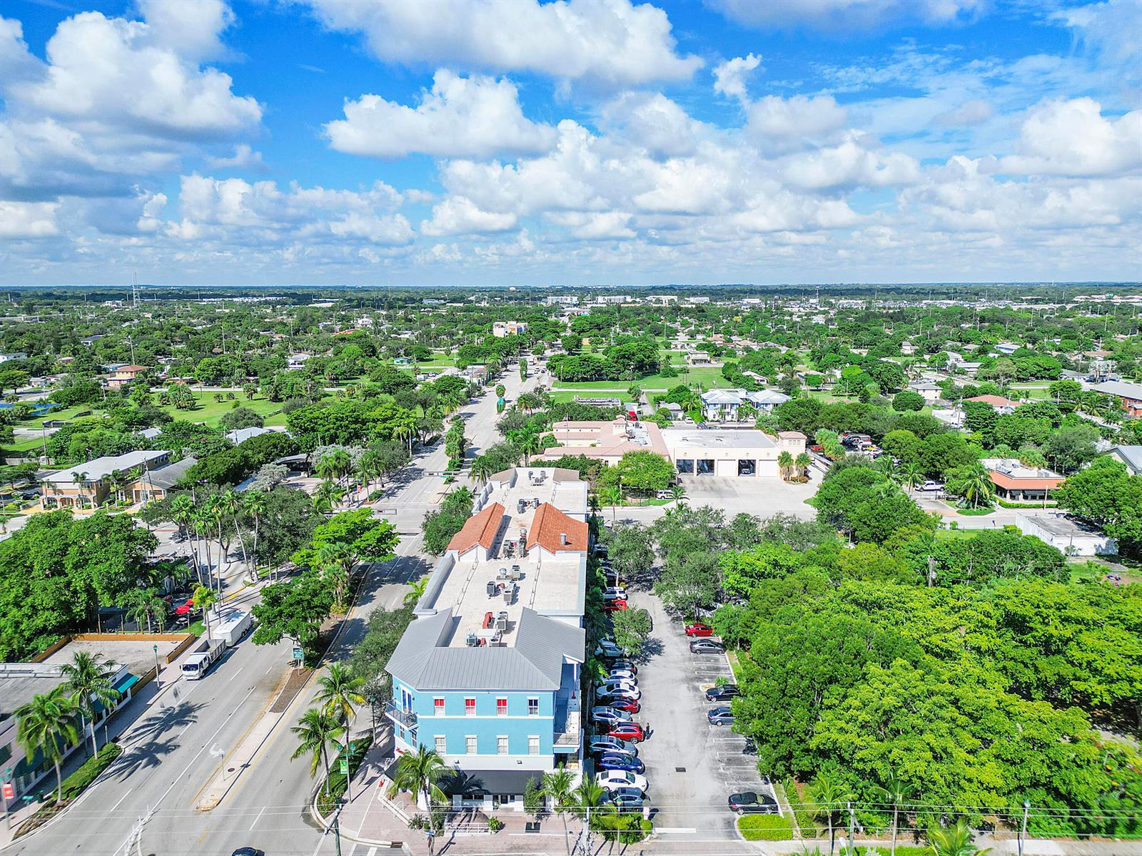 An aerial view shows a blue multi-story building with a parking lot and surrounding greenery — 401 W Atlantic Avenue # R9, Delray Beach FL 33444, DELRAY BEACH, FL