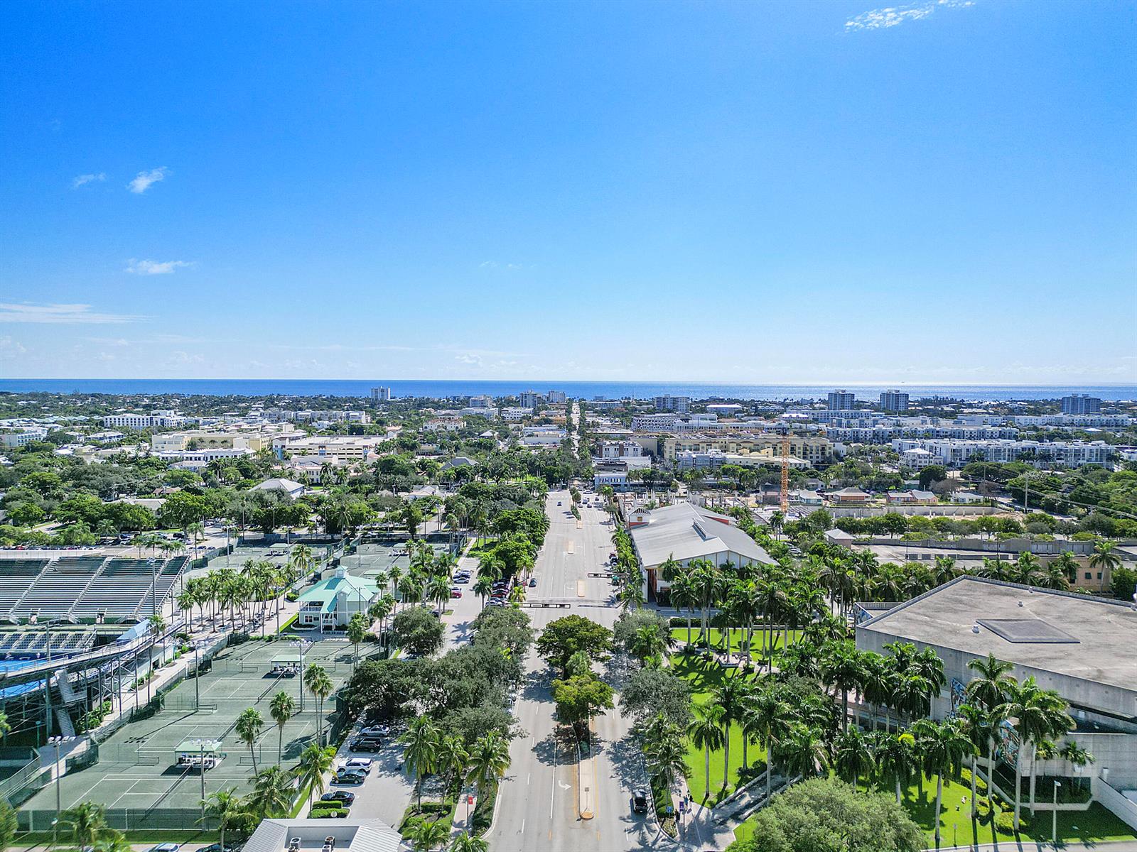 An aerial view shows a city street lined with palm trees, tennis courts, and buildings — 401 W Atlantic Avenue # R9, Delray Beach FL 33444, DELRAY BEACH, FL