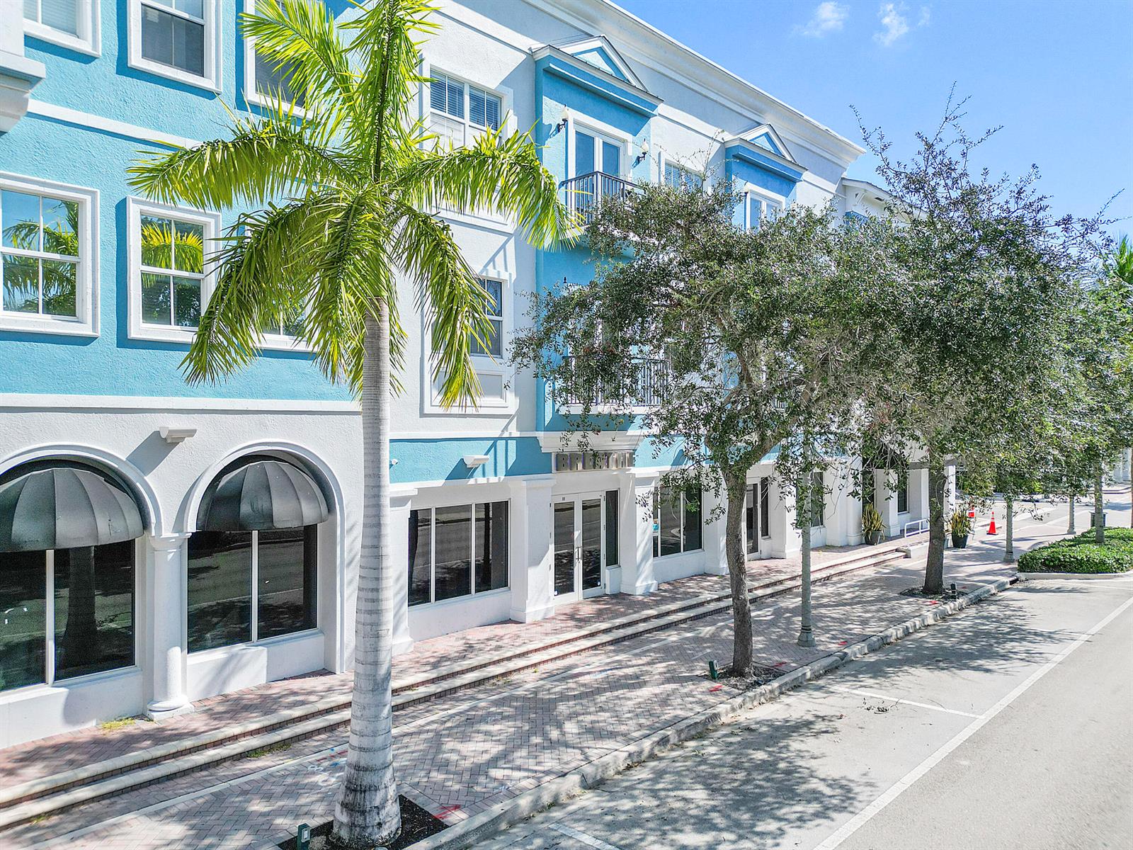A multi-story blue and white building features arched storefront windows and a palm tree — 401 W Atlantic Avenue # R9, Delray Beach FL 33444, DELRAY BEACH, FL