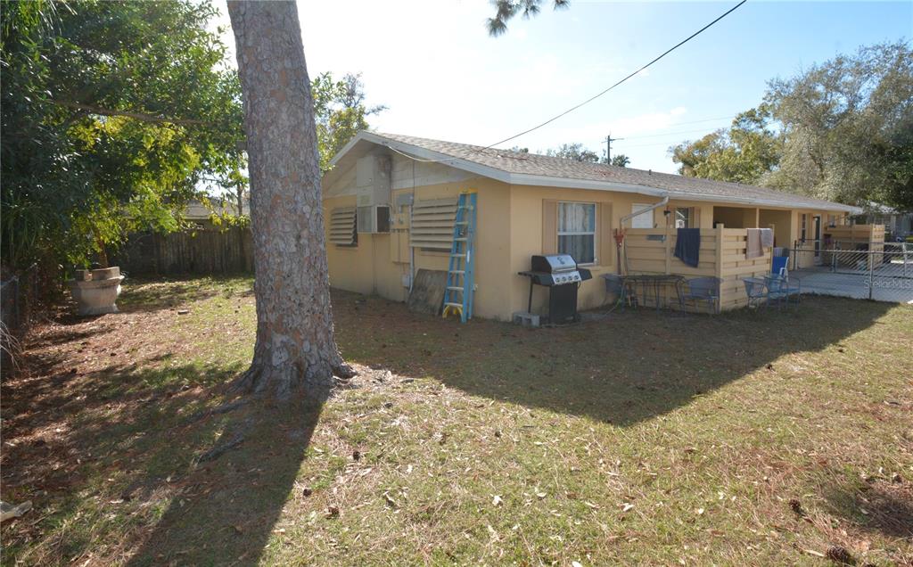 The exterior of a single-story house features a yellow stucco wall, a grill, and a ladder — 2100 9TH STREET, SARASOTA, FL