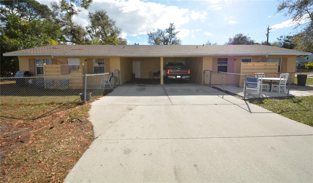 A single-story duplex with a shared central carport and chain-link fenced front yards — 2100 9TH STREET, SARASOTA, FL