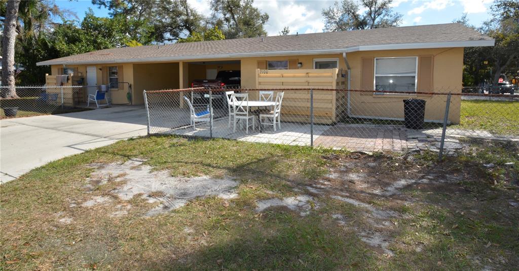 A single-story duplex with a carport, a fenced patio area, and a paved driveway — 2100 9TH STREET, SARASOTA, FL